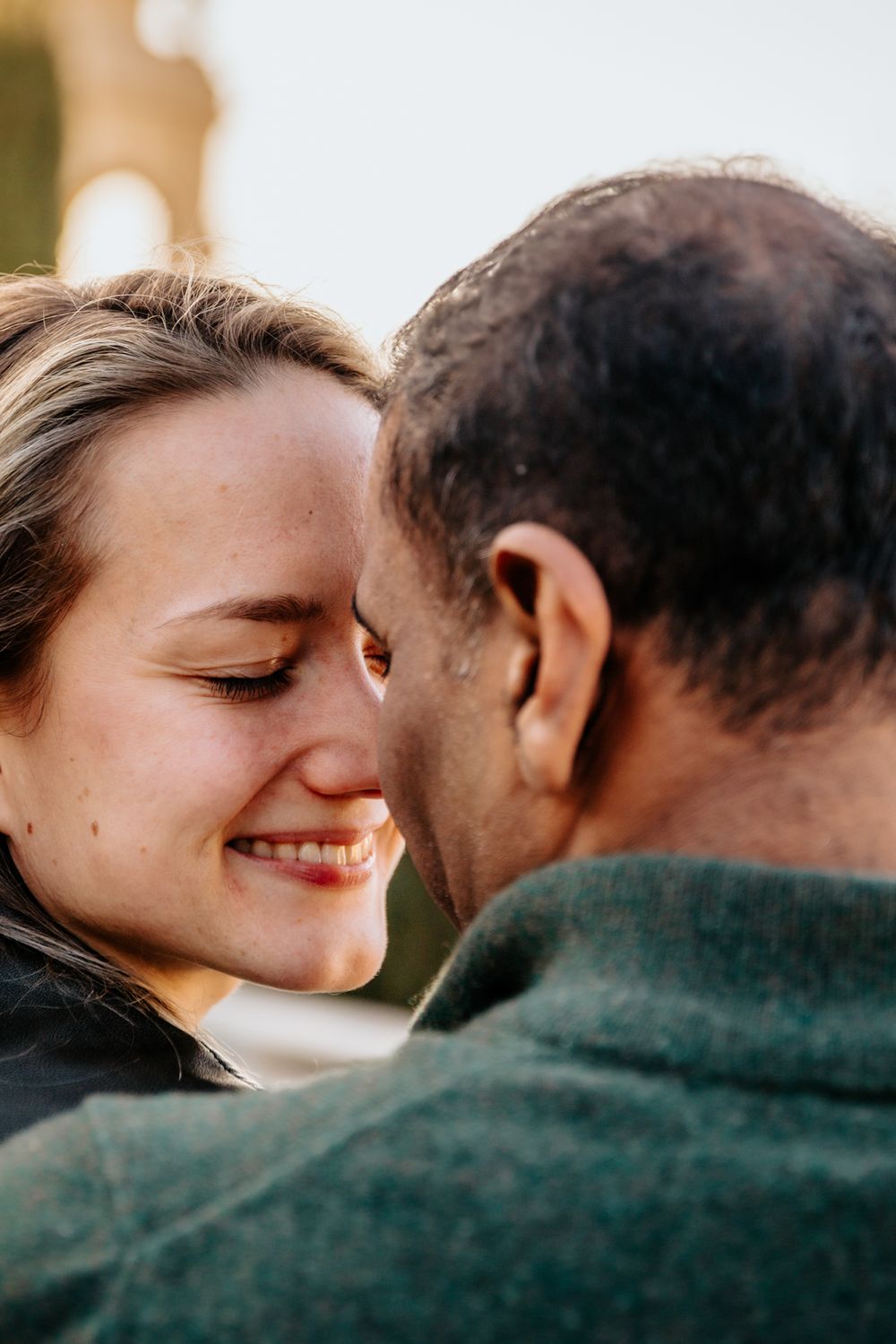 Portrait of the couple standing close with the city in the background.