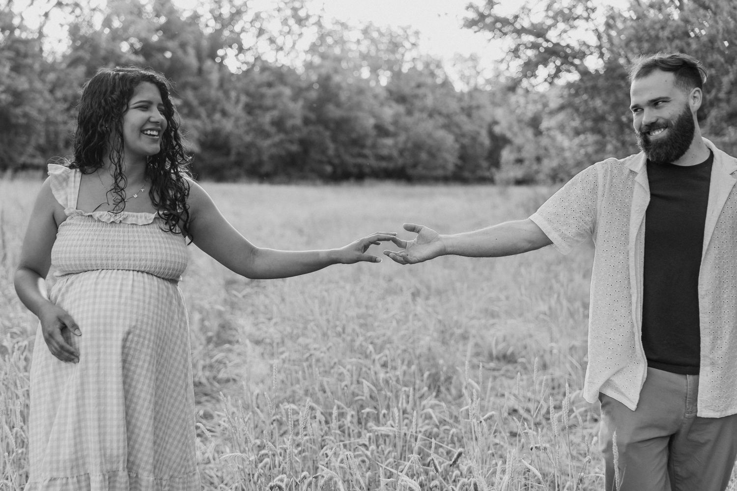 Black and white photo of couple holding hands in a meadow.
