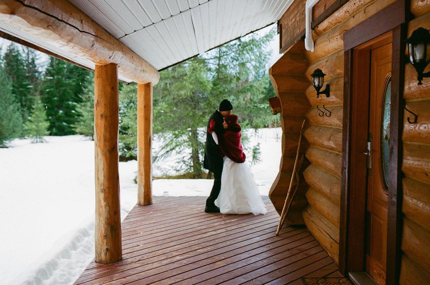 35 mm film photo of bride and groom dancing on the porch of a log cabin in the snow