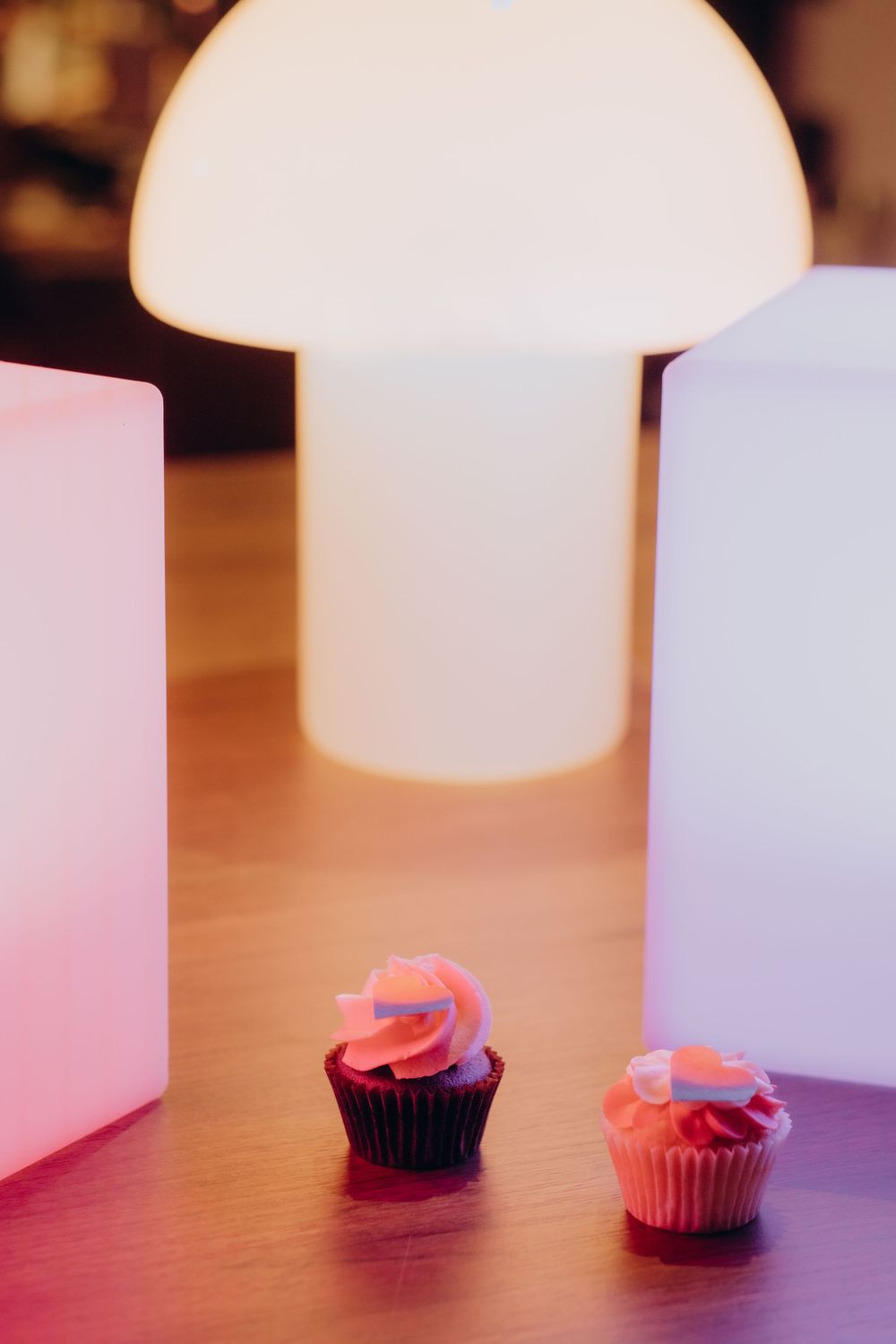 two cupcakes sitting on a table in neon light captured by experienced event photographer in Stockholm