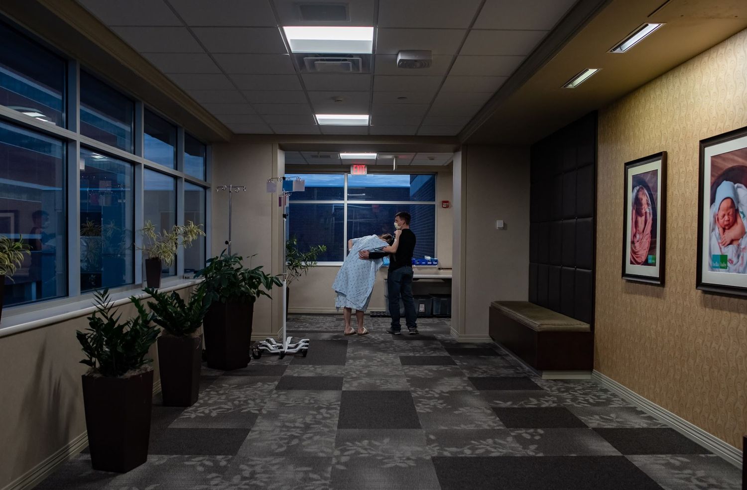A dimly lit Bryan hospital hallway with potted plants and windows.