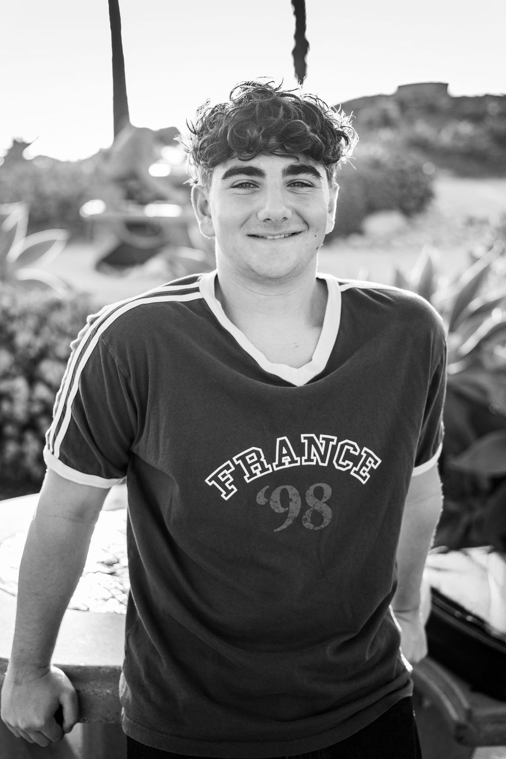 Young man smiling in a France 98 jersey, black and white outdoor portrait photo.