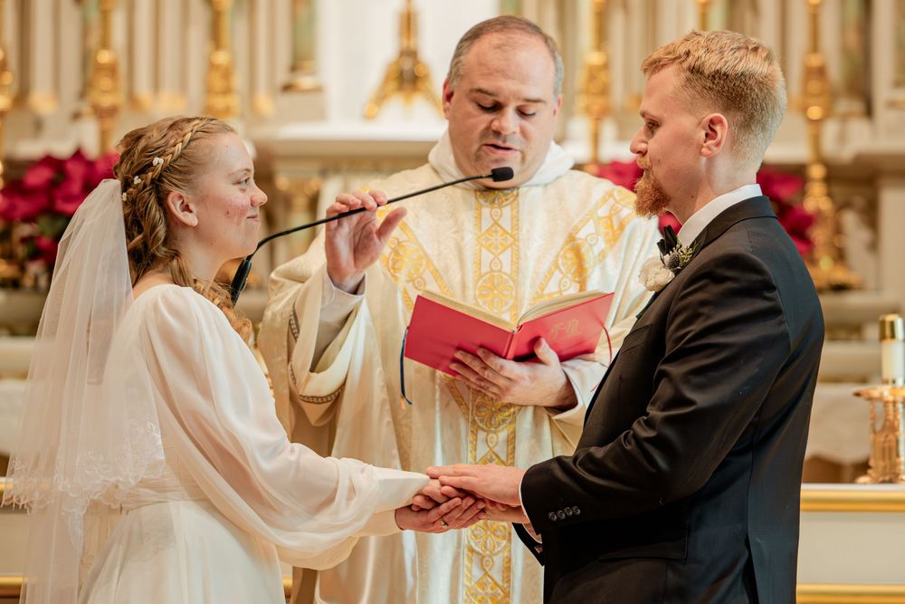 Bride and groom exchange vows before a priest during a traditional church wedding ceremony.