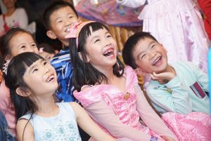 Happy children laughing together at a party wearing colorful party outfits.