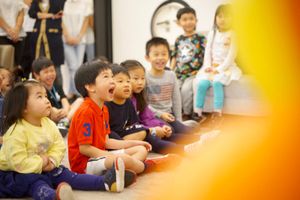 Group of kids sitting and watching something with excited expressions in a classroom setting.