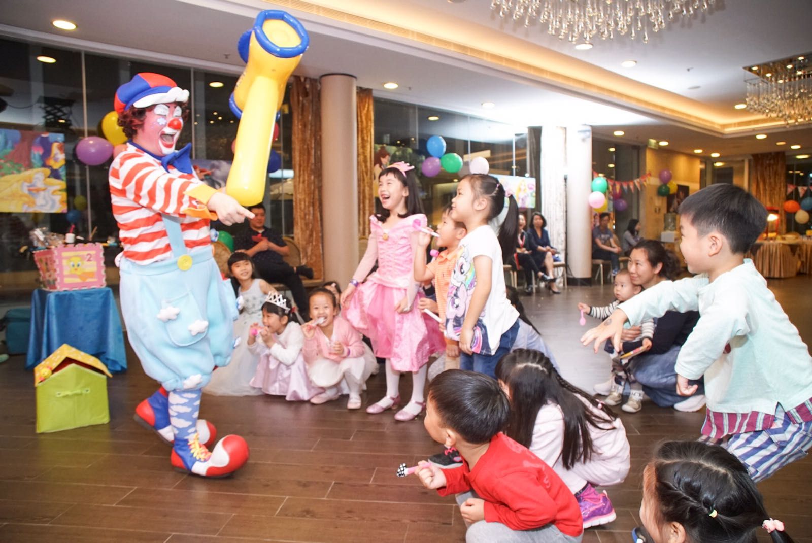 Clown entertains children with balloon art at an indoor party.