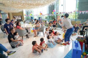 Children and adults gather in a decorated room for a festive party celebration with streamers and balloons.