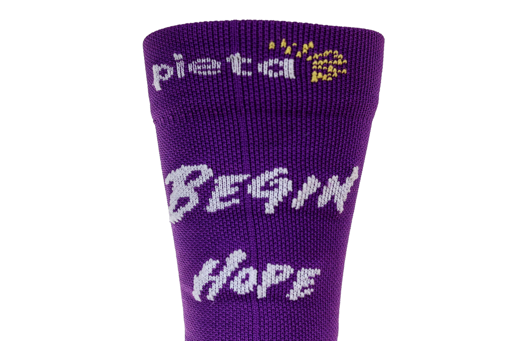 Close-up of purple Pieta sock displaying 'Begin Hope' text for suicide prevention awareness.