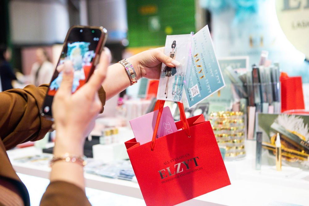 Person photographing red PYZYI shopping bag with beauty products at a cosmetics retail store display.
