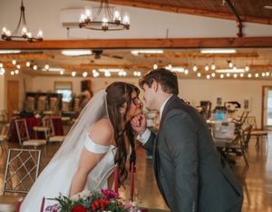 Bride and groom sharing a romantic kiss at their wedding reception venue decorated with string lights.