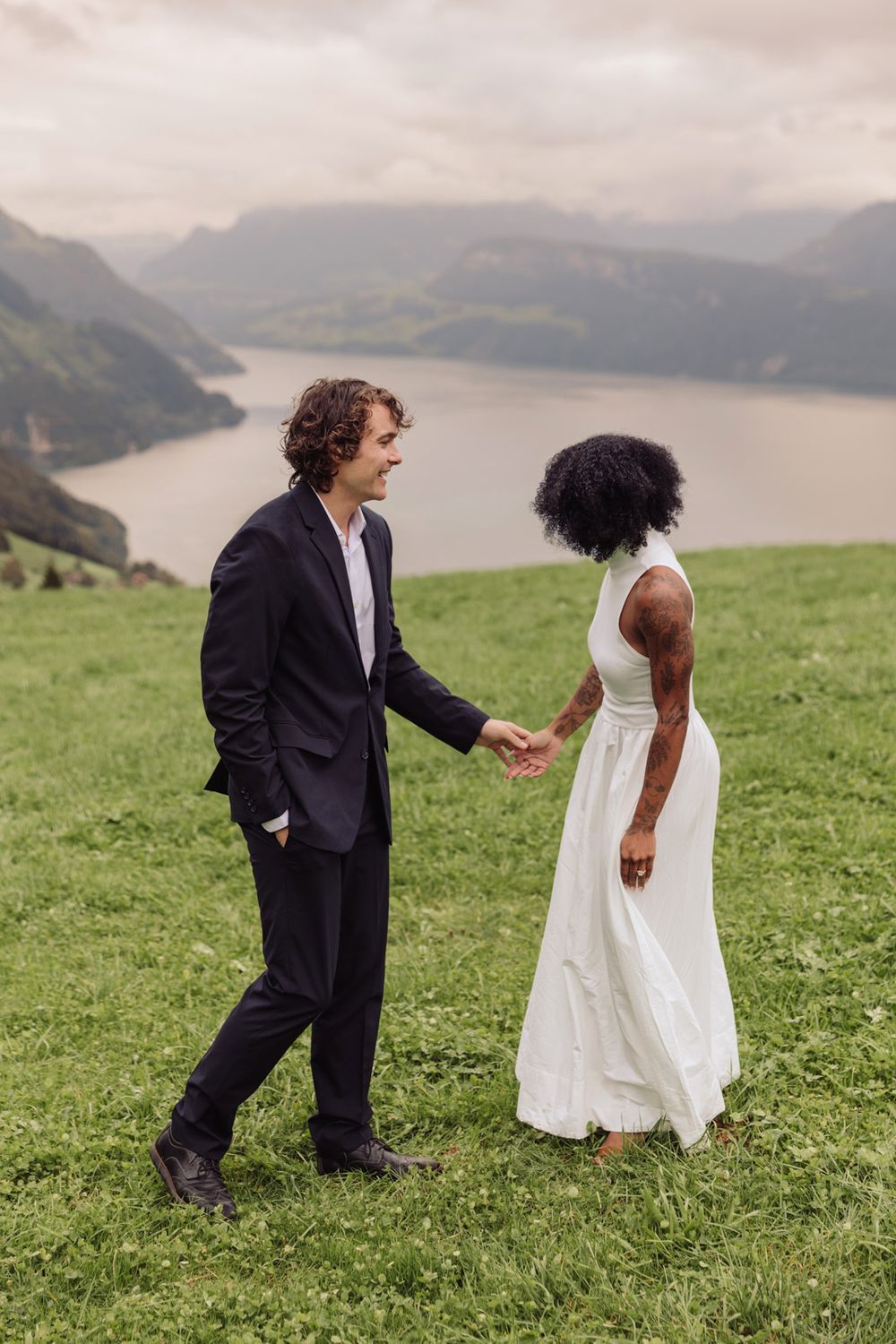 Full-length portrait of a man and woman holding hands on a mountain ridge during an engagement session.