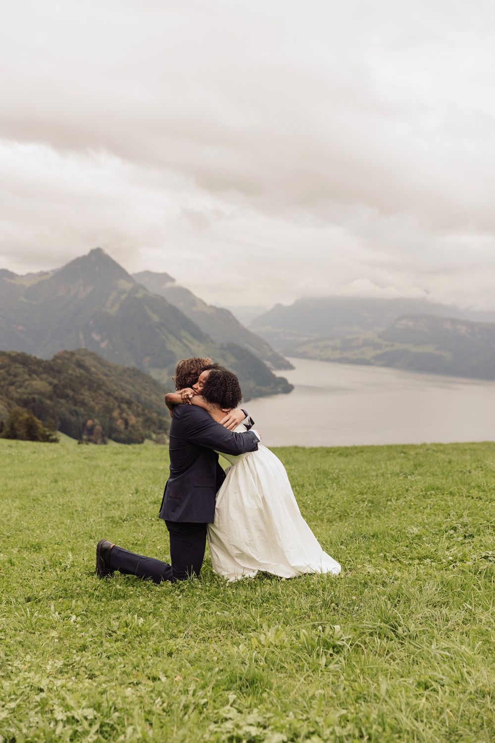 Distant view of a marriage proposal happening on a green hill in a beautiful natural landscape.