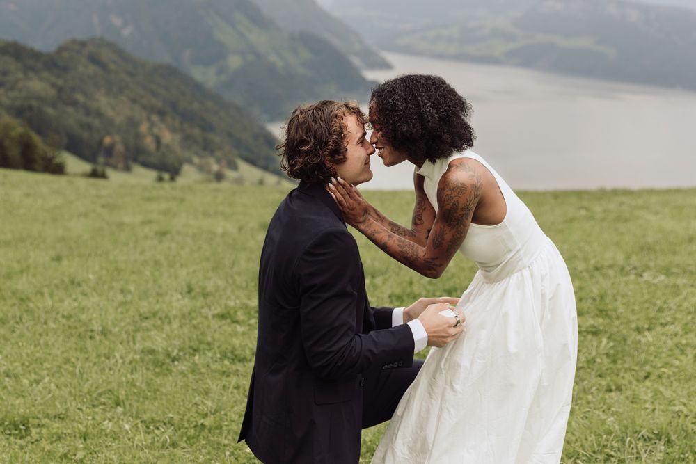Close-up of a surprised woman leaning in toward her partner as he proposes outdoors.