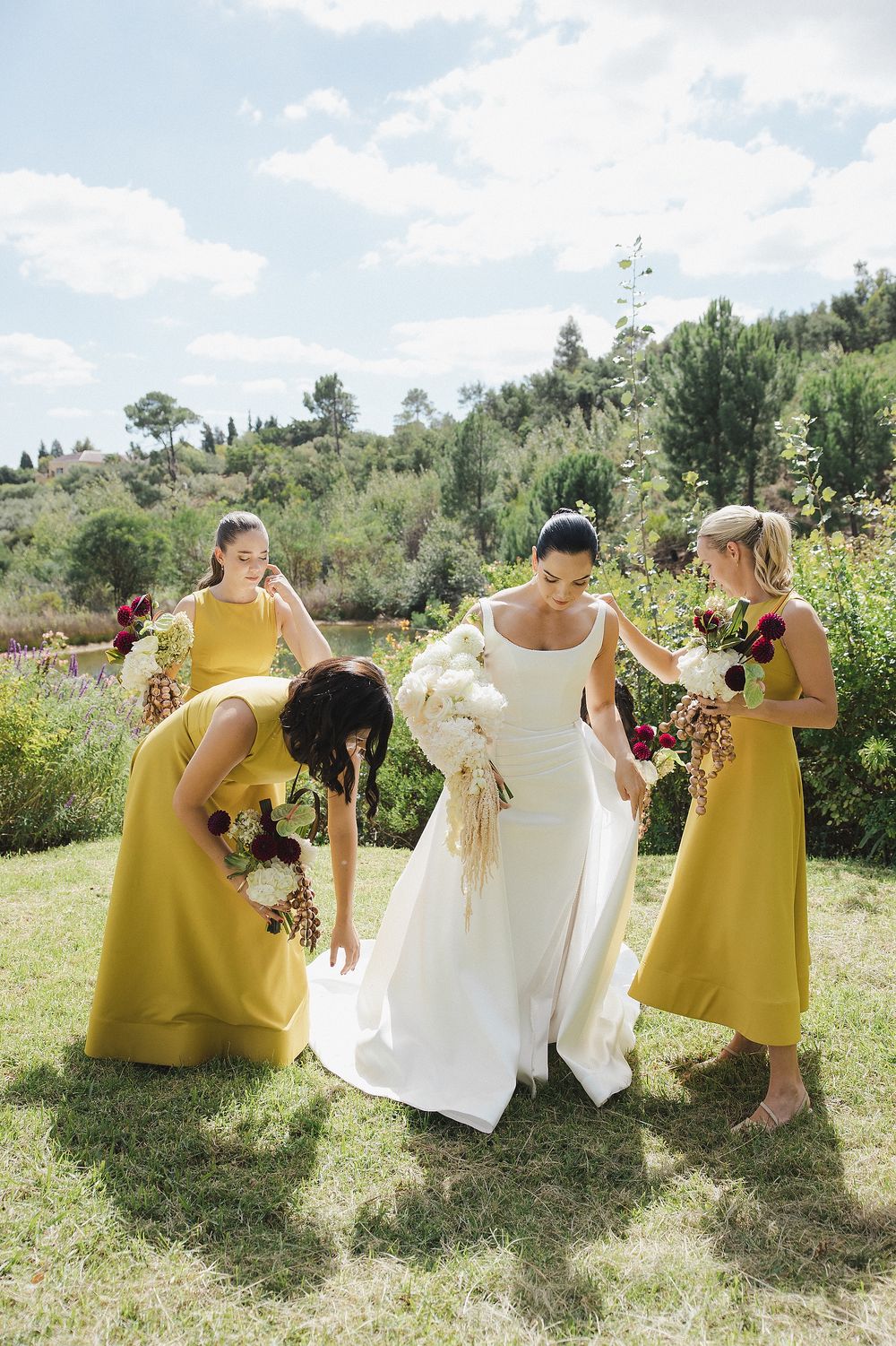 Bride Lizré walking through vineyards in a sophisticated modern wedding gown and bridesmaids