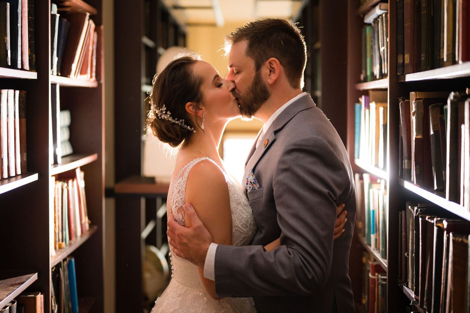 Romantic wedding photos captured in library setting with dark wood bookshelves.