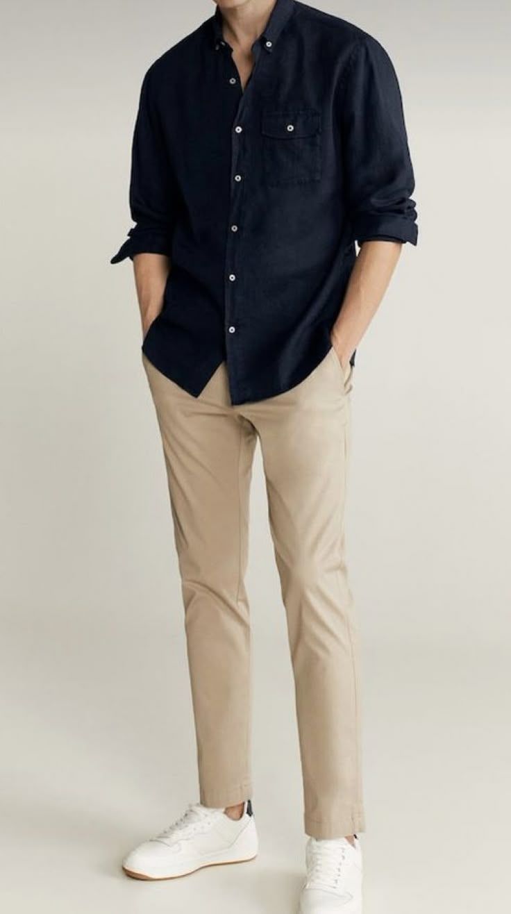 Man wearing navy linen shirt with chest pocket, beige chinos, and white sneakers in a smart casual outfit.