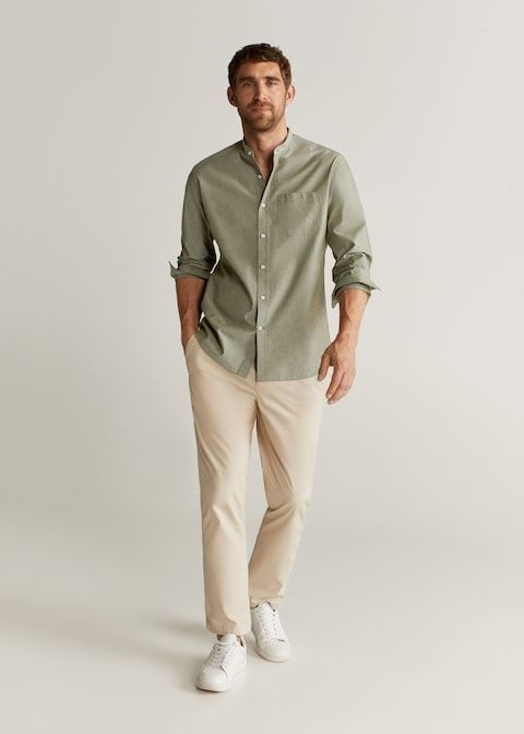 Man wearing a sage green mandarin collar shirt with beige chinos and white sneakers in a casual smart outfit.