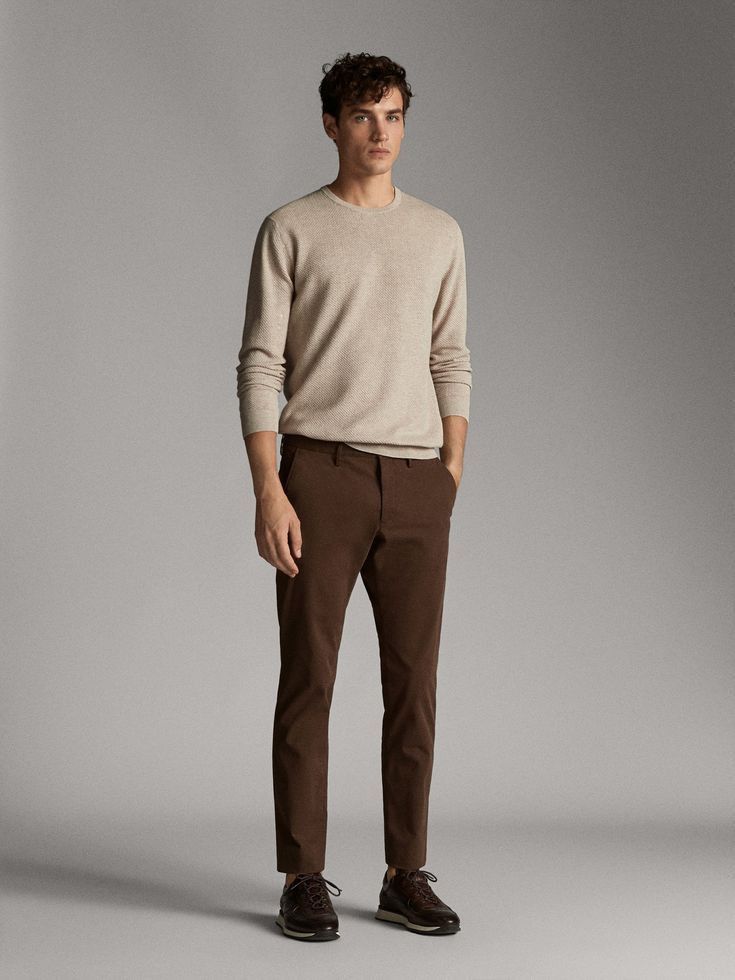 Man wearing a beige crew-neck sweater with brown slim-fit chinos and dark brown lace-up dress shoes.