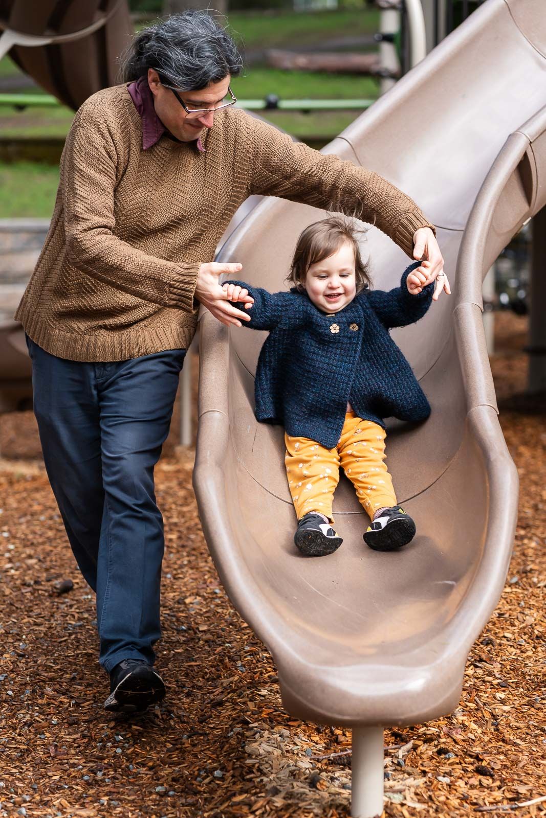 Father helping child down the slide.