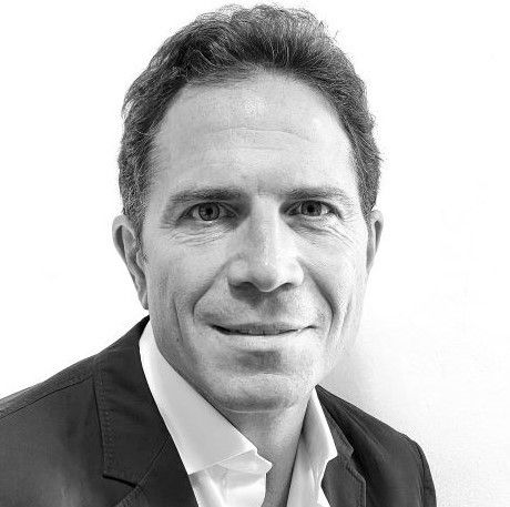 Black and white professional headshot of a middle-aged man in a blazer smiling confidently.