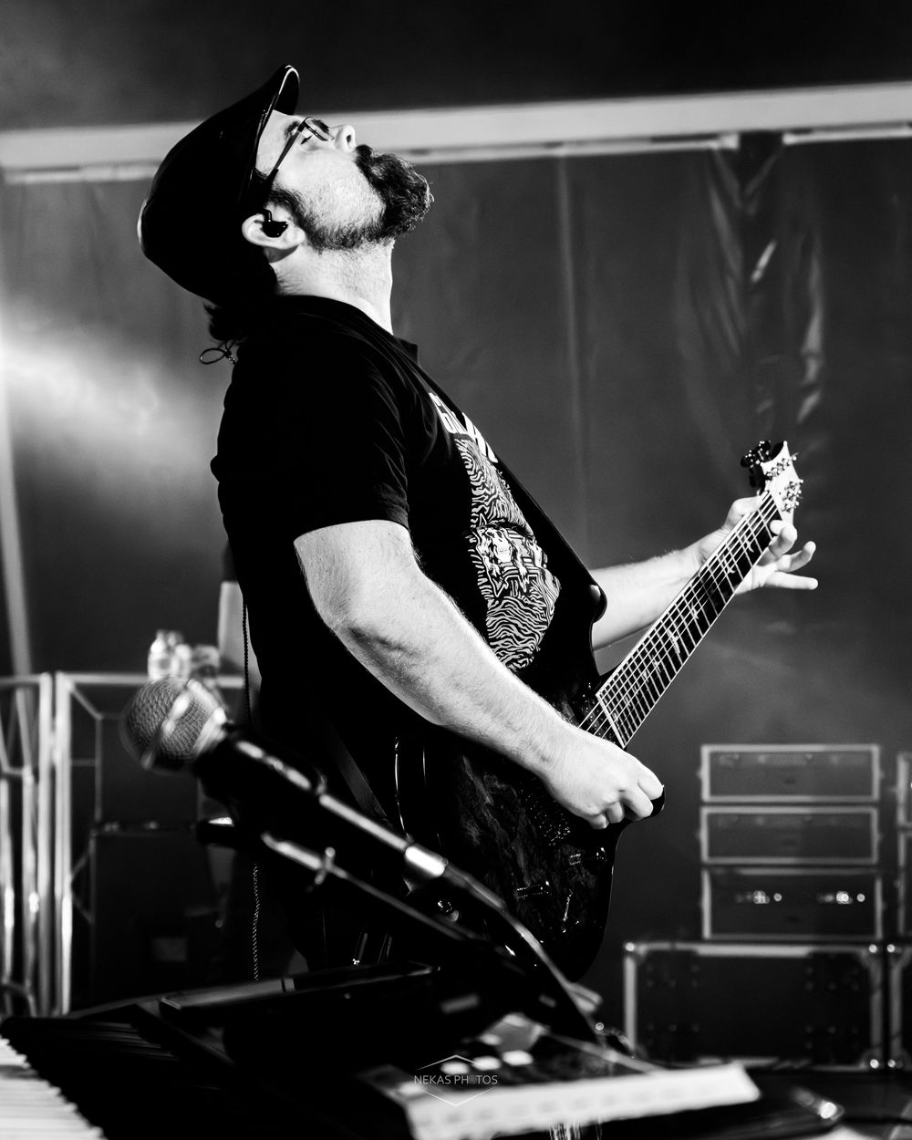 Black and white photo of a male guitarist wearing a cowboy hat, passionately playing electric guitar on stage.
