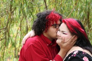 Couple sharing a tender kiss on the cheek during a natural and candid engagement session