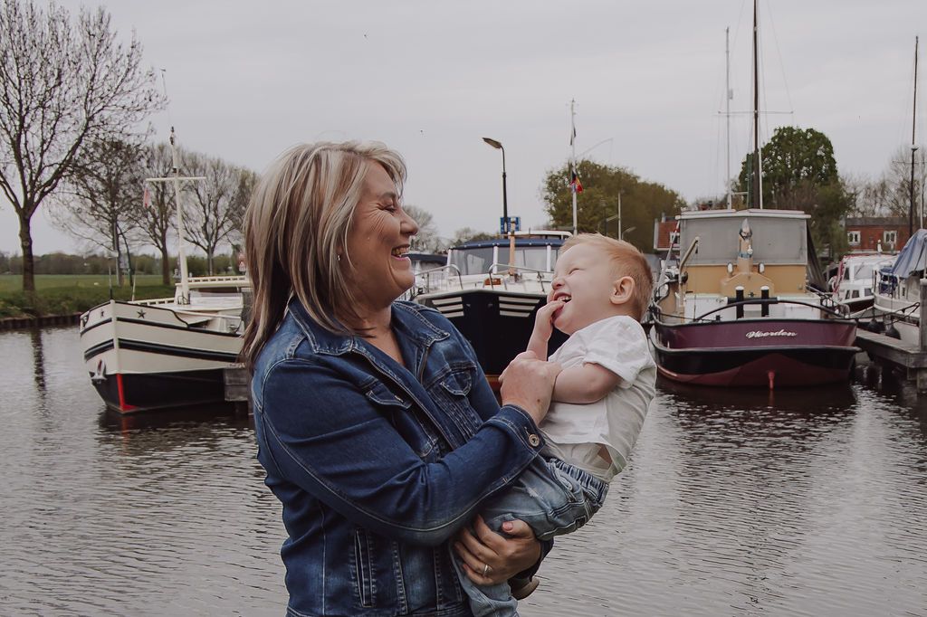 Grandmother holding grandchild during outdoor family session in Woerden