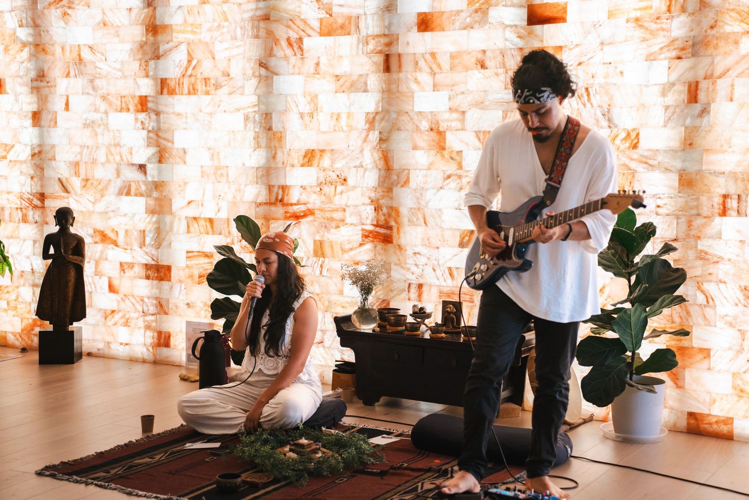 A musician plays guitar during a sound healing session in a salt cave with singing bowls and plants. Vista, CA