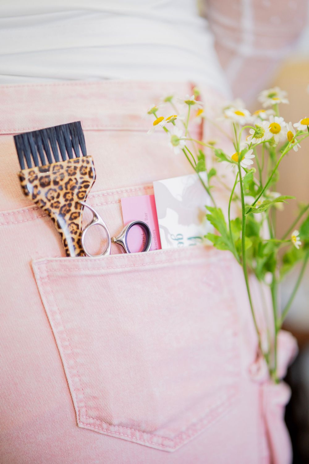 Close-up of pink cargo pants pocket with leopard print brush, scissors and flowers.