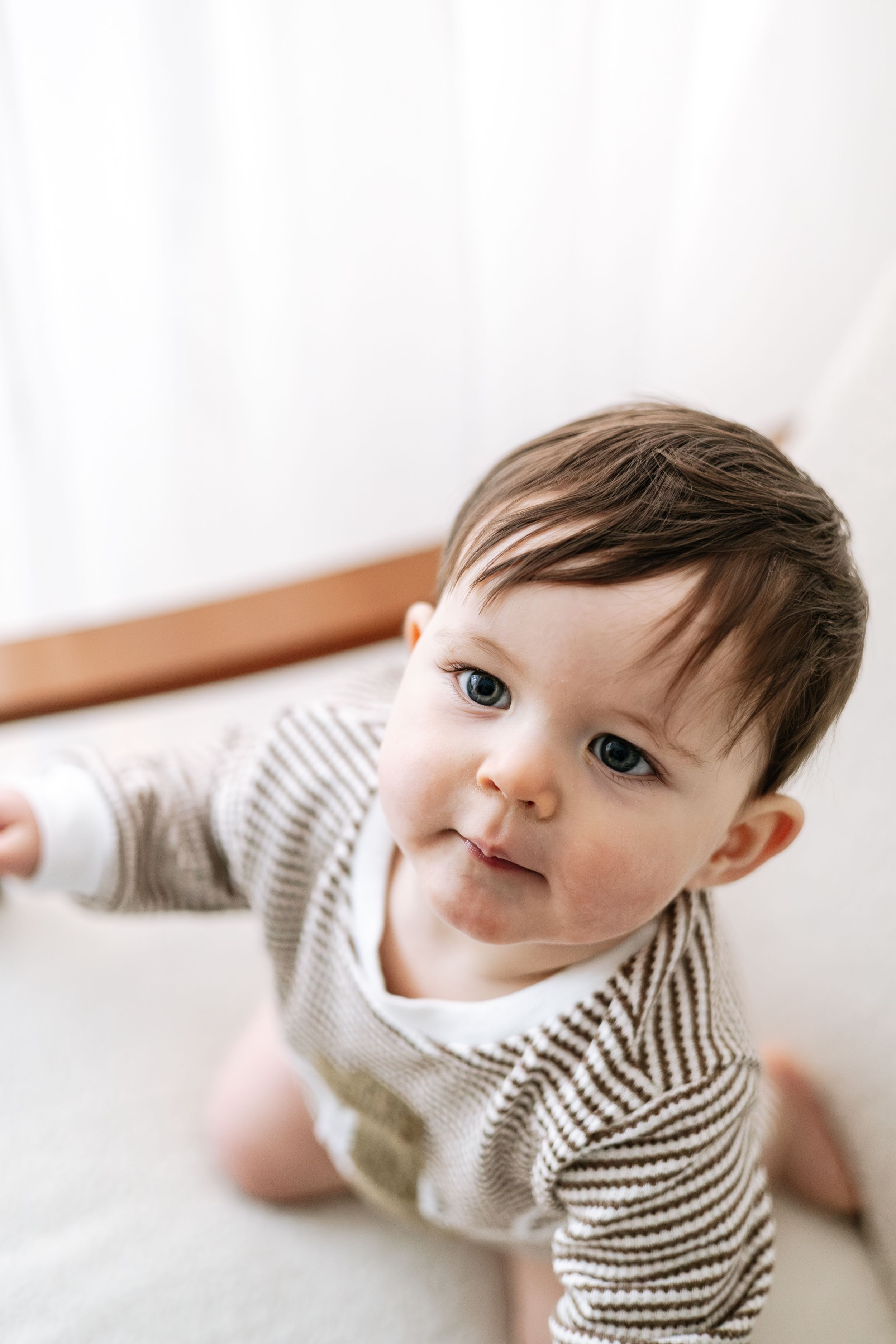 Adorable baby with dark hair and blue eyes wearing a striped onesie, first birthday photography Nottingham