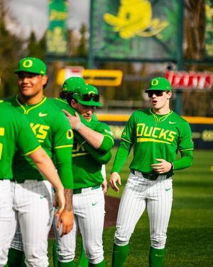 Oregon Ducks baseball players in bright green uniforms celebrate on the field during a game.