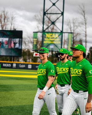 Oregon Ducks baseball players in green uniforms walk on field during NCAA Tournament game at PK Park in Eugene.