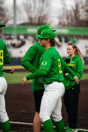 Oregon Ducks baseball players in green uniforms celebrate on the field during a college baseball game.