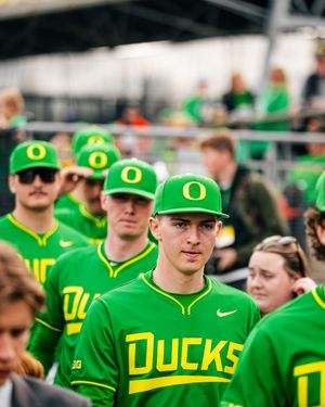 Oregon Ducks baseball players in bright green uniforms and caps walk through a stadium crowd.