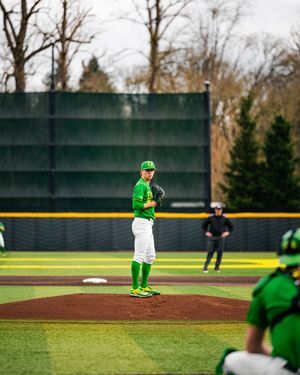 Oregon Ducks pitcher in green uniform stands on mound at PK Park during a college baseball game.
