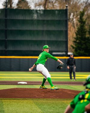 Oregon Ducks pitcher winds up on the mound in green uniform during a college baseball game at PK Park.