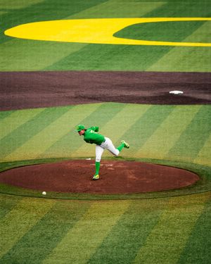 Baseball pitcher in green uniform mid-throw on mound at vibrant green and yellow striped field.