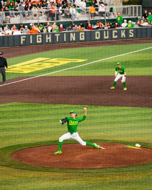 Oregon Ducks pitcher winds up on the mound at a Fighting Ducks baseball game in bright green uniforms.