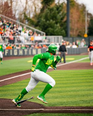 Oregon Ducks baseball player in bright green uniform sprinting the bases during a college baseball game.