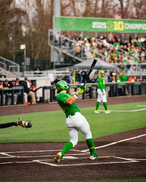 Oregon Ducks baseball player in green uniform batting during a 2025 Big Ten Championship game at a packed stadium.