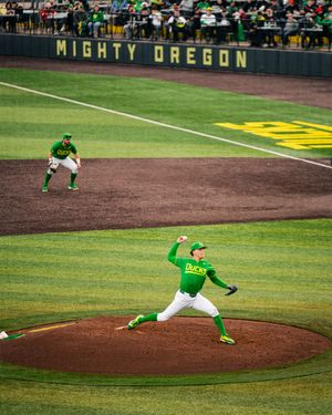 Oregon Ducks pitcher winds up on the mound at Mighty Oregon baseball stadium in bright green uniforms.