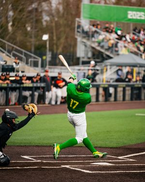 Oregon Ducks baseball player #17 in green uniform batting during a college baseball game at a packed stadium.