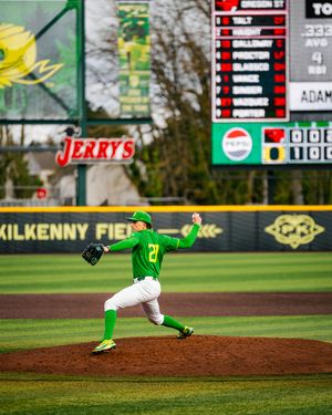 Oregon Ducks pitcher in green uniform winds up to throw at Kilkenny Field during a college baseball game.