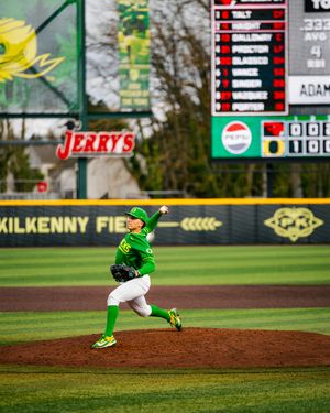 Oregon Ducks pitcher in green uniform delivers a pitch at Kilkenny Field during a college baseball game.