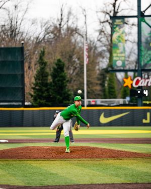 Oregon Ducks pitcher in green uniform delivers a pitch from the mound at a college baseball game.