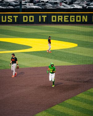 Oregon Ducks baseball game at PK Park with players on field and Just Do It Oregon sign in background.