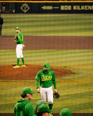 Oregon Ducks baseball players in green uniforms on the field at Bob Kilkenny Park during a college baseball game.