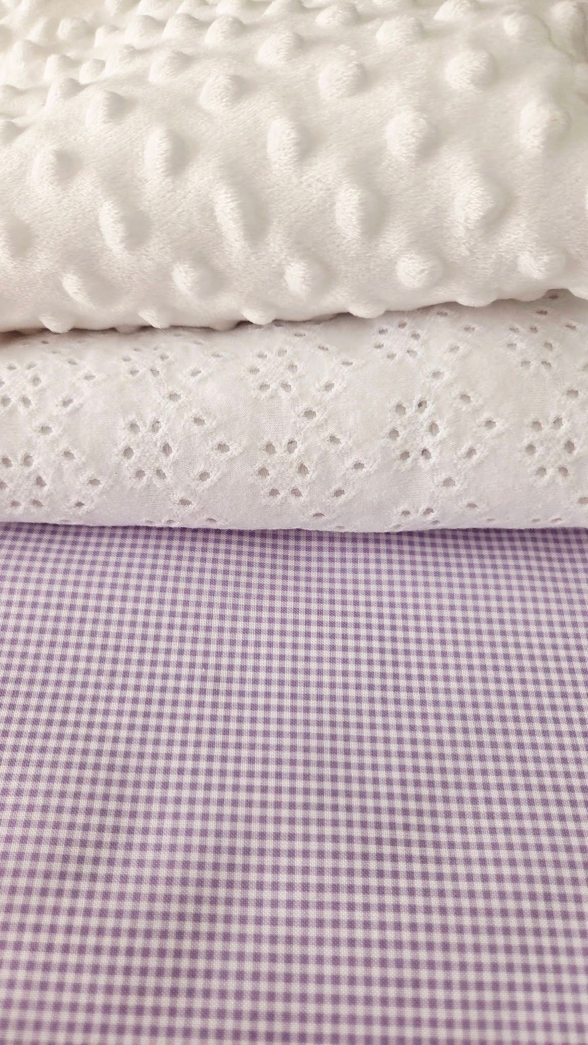 Three layered fabrics: white minky dot, white broderie anglaise, and lavender gingham check textile.