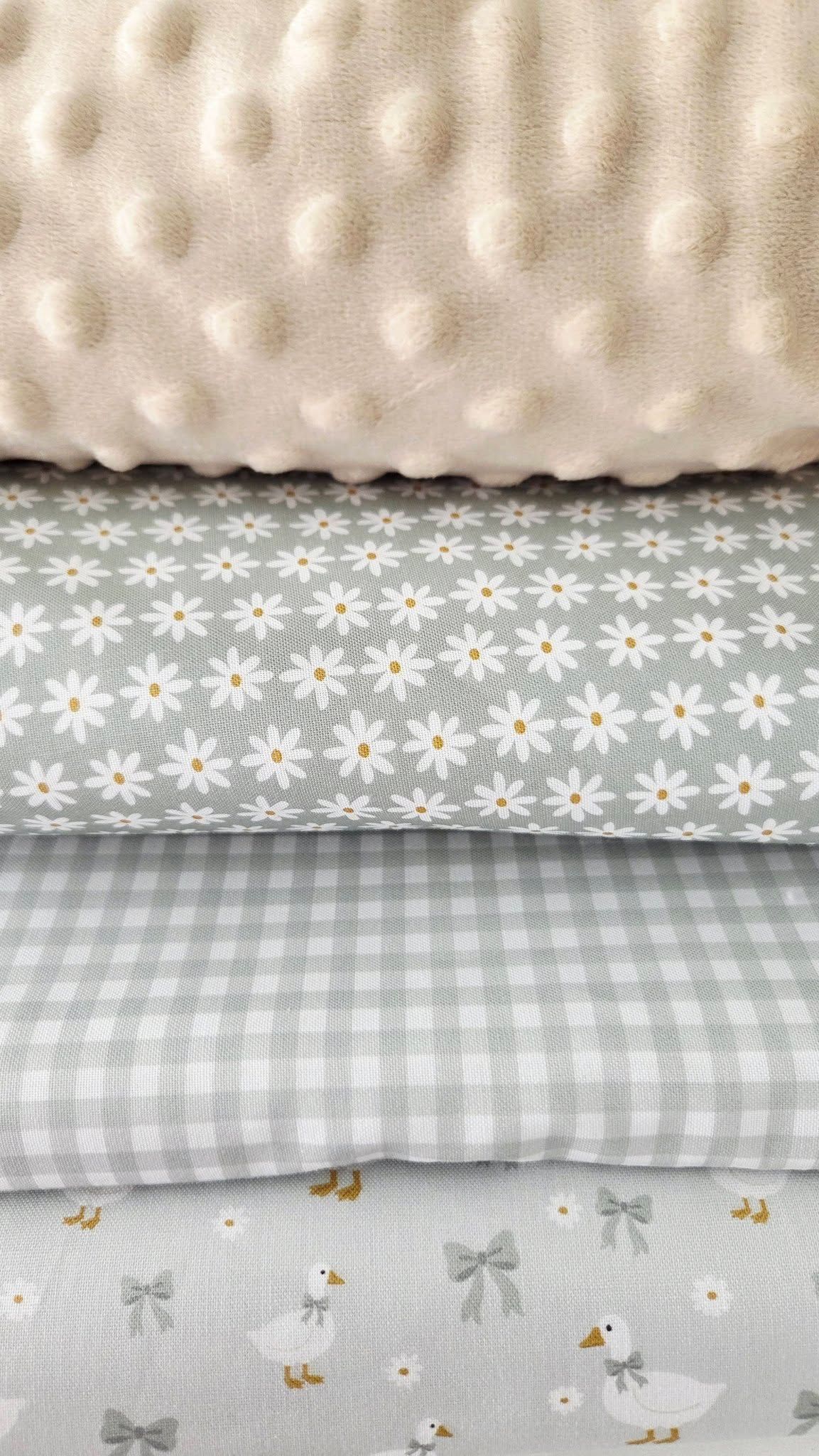 Stack of gray and white baby fabrics featuring minky dot, daisy floral, gingham check, and duck print patterns.