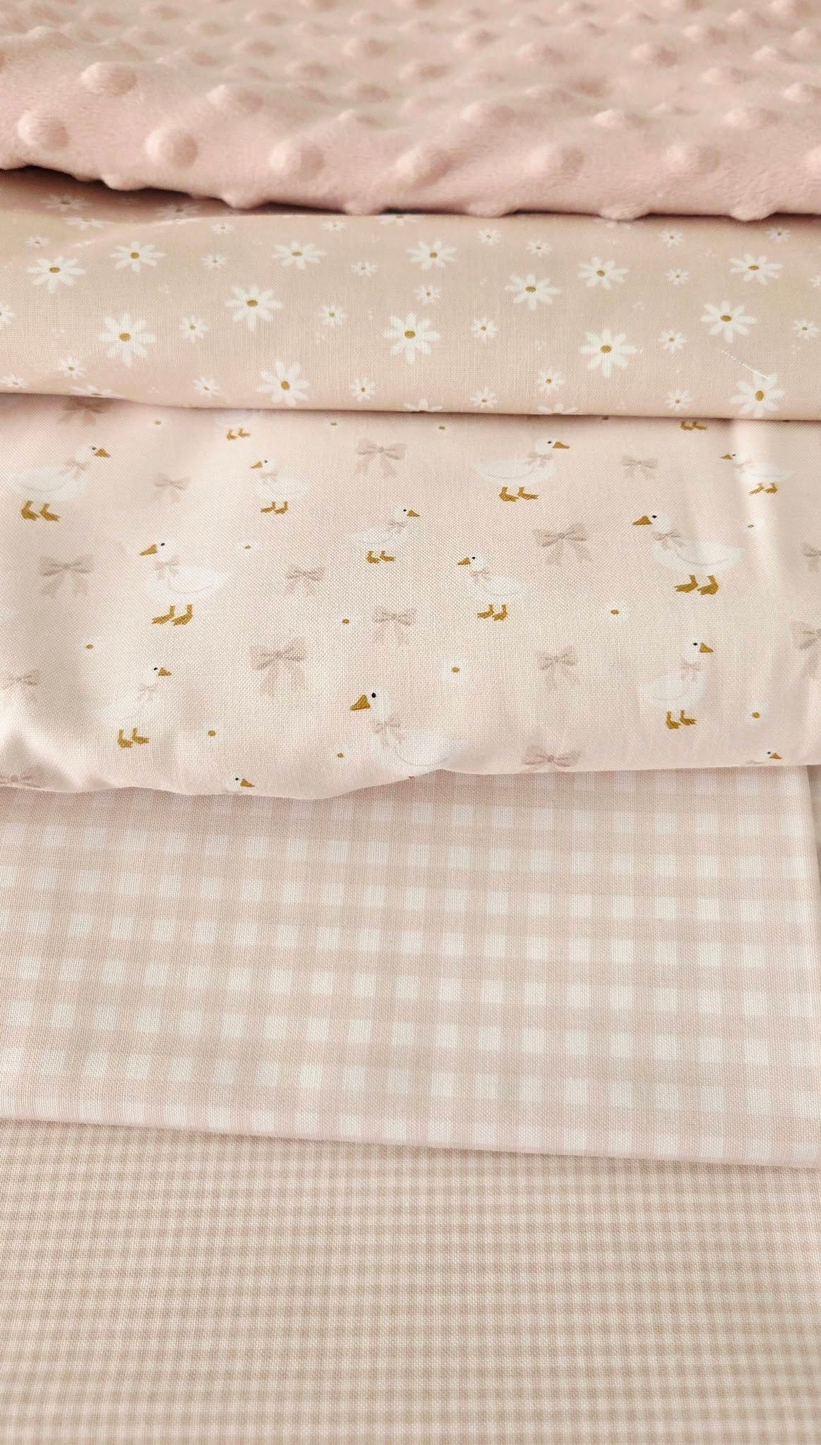 Four pink fabric swatches featuring minky dots, daisy print, geese with bows, and gingham check patterns.